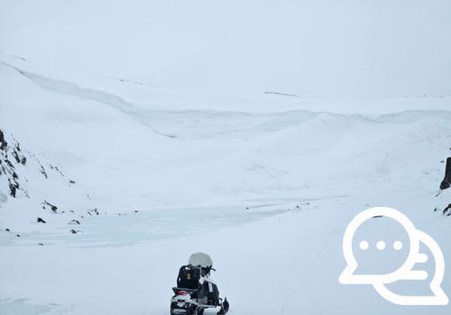 Une motoneige vide dans une vaste étendue enneigée.